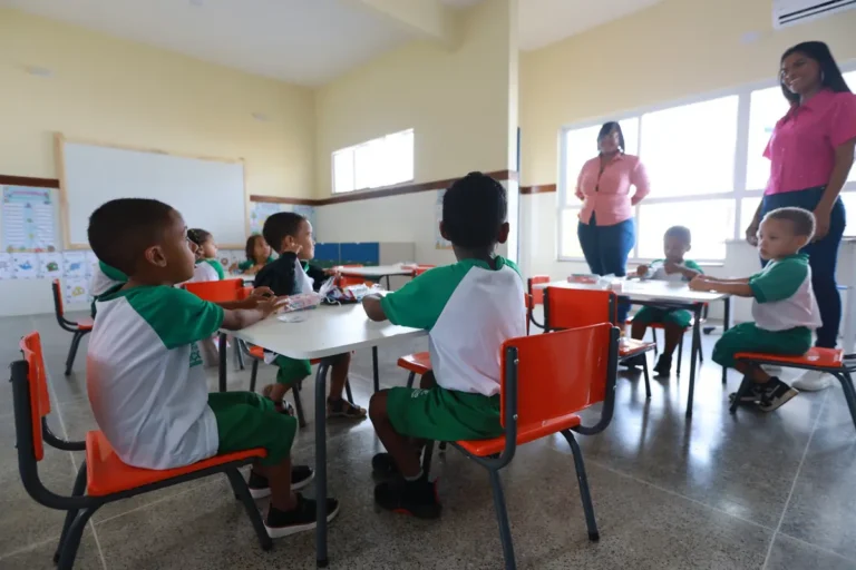 Young children at small tables in a bright childcare classroom with two educators