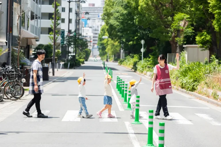 Children and adults crossing a quiet, tree-lined city street