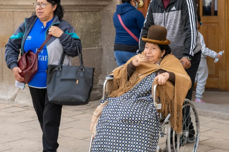 An older woman in a wheelchair with relatives on a city pavement