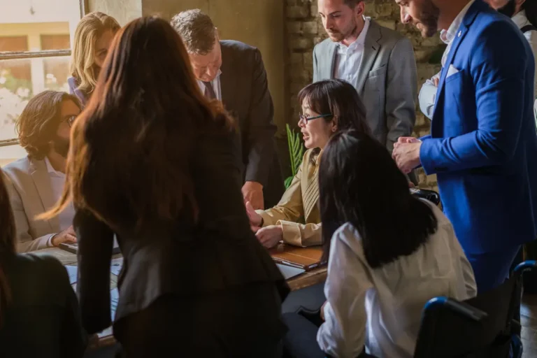 People gathered around a meeting table, talking over documents